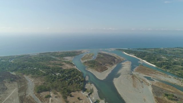 Aerial view of rver flowing into the sea in Philippines,Luzon. ropical landscape with sandy coast and river among farmer fields flowing into the blue ocean