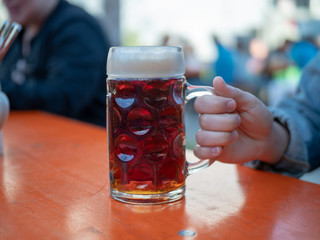 Woman hand holding large beer mug at beer garden