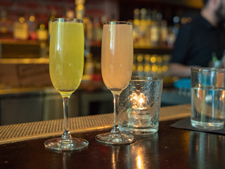Two wineglasses filled with mimosa drinks sitting on a bar counter top