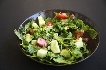 Summer salad with fresh vegetables and greens in a bowl. Closeup.
