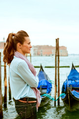 Woman standing in profile in Venice with gondolas in background