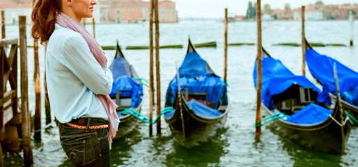 Fototapeta na wymiar Woman standing in profile in Venice with gondolas in background
