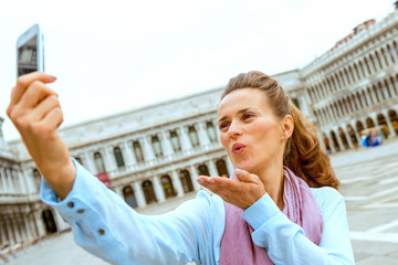 Young woman blowing kiss and making selfie on piazza san marco i