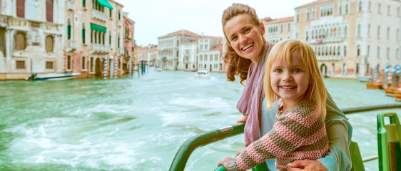 Happy mother and baby girl travel by venice water bus