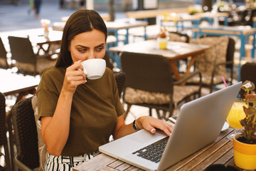 Beautiful woman enjoying in coffee with laptop on the table in front in cafe