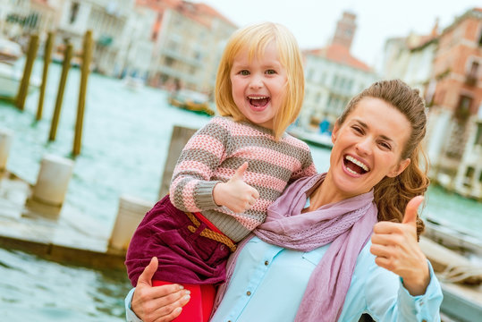 Happy mother and baby girl standing on embankment in venice, ita