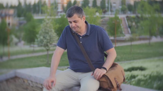 A tired middle-aged man sat down to rest after climbing stairs. A man checks on a smartphone the number of steps.