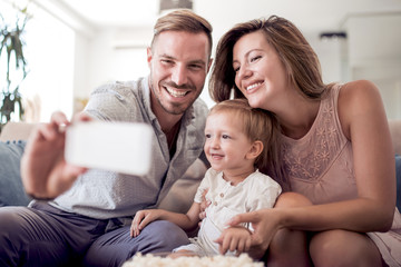 Obraz premium Happy family on sofa at home take selfie