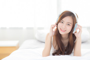 Naklejka premium Beautiful asian young woman enjoy listen music with headphone while lying in bedroom, relax girl with earphone internet online, leisure and technology concept.