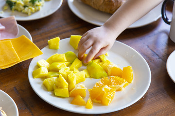 hand of a toddler having fruits for breakfast