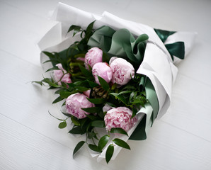 Bouquet of pink peony flowers with green leafs on grey
