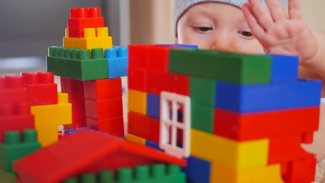 Kid playing with colored blocks of a constructor on floor in children room.