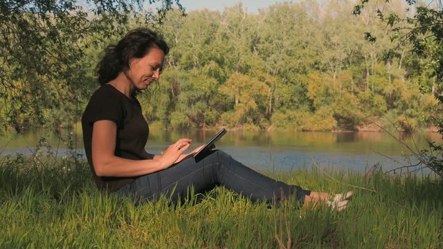Woman with a tablet on nature.