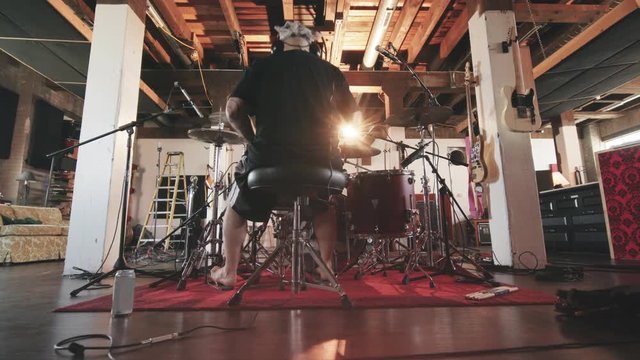 Behind Drummer in Recording Studio Move In. a wide angle low shot of someone drumming in a recording studio as the camera moves in with lens flare