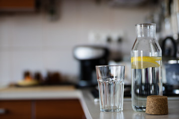 Fresh water with lemon. A refreshing drink in a glass container standing in the kitchen.