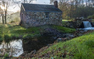 Old abandoned house with sun rays passing through the tree on the background and pond on the...