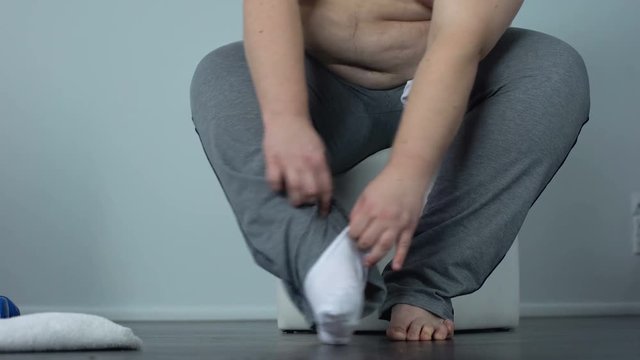 Obese male hardly putting socks, lack of physical activity, sedentary lifestyle