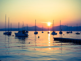 Sailboats moored in Lake Garda, Italy, at sunset.