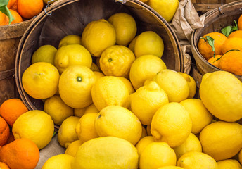 full frame close up of wooden buckets filled with ripe brightly colored lemons and oranges at a farmer's market