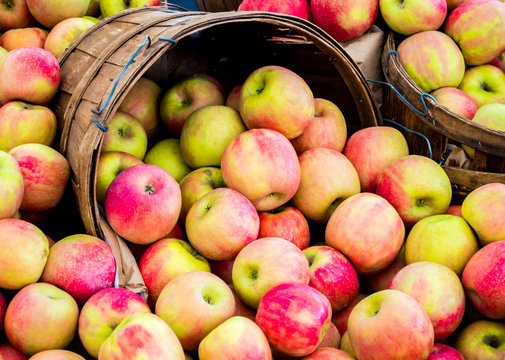 full frame close up of wooden buckets filled with ripe red and green apples at a farmer's market