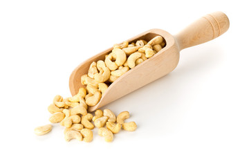 Heap of raw, organic, whole cashew nut kernels in wooden scoop over white