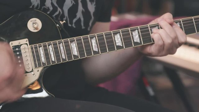 Guitarist Playing Electric Guitar Tilt Up. a close up shot of a guitarist playing an electric guitar and tilting up to face