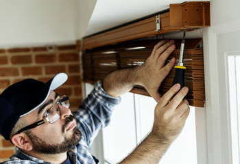 People installing window curtain