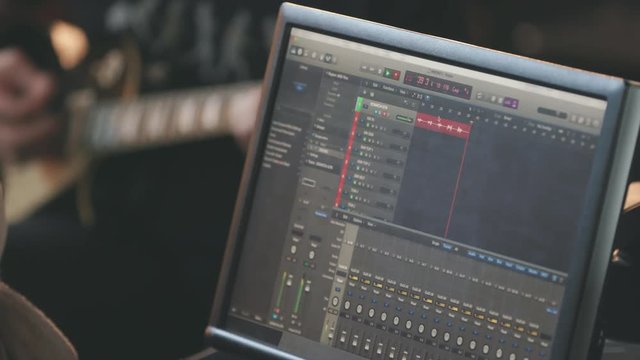 Guitar Recording Close Up of Monitor of Audio Tracks . a close up view of a computer monitor recording a track from a guitar player in the background