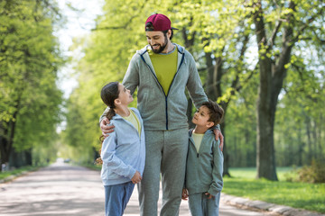Fototapeta premium smiling father embracing daughter and son in park