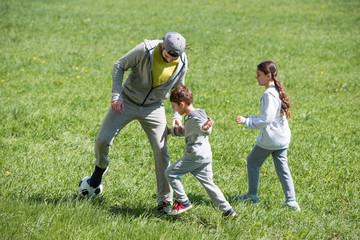 father playing football with daughter and son in park