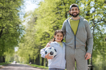Fototapeta premium smiling father and daughter with ball in park