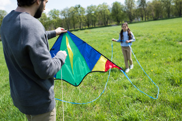 cropped shot of father holding kite with daughter in park