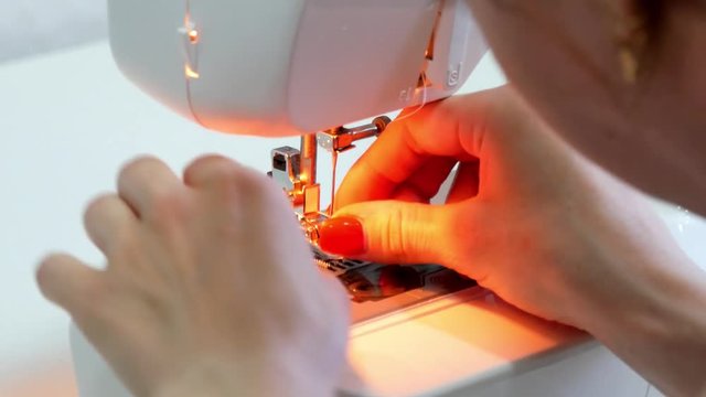 Woman sews on the modern sewing machine. Sewing machine sews close up