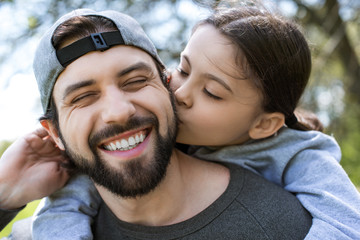 daughter kissing cheek of smiling father