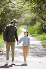 Obraz premium smiling father and daughter walking and holding hands in park