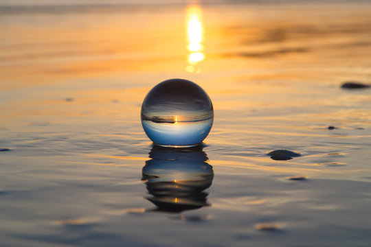 sunset creative photography on beach with crystal ball with reflections