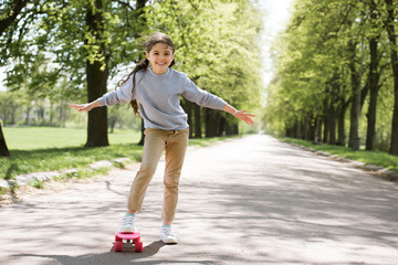 little child with skateboard on path in park