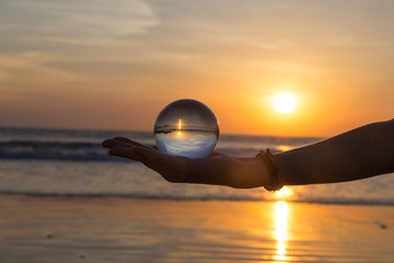 Creative photography Landscape concept with crystal ball or esphere in hand during sunset on beach