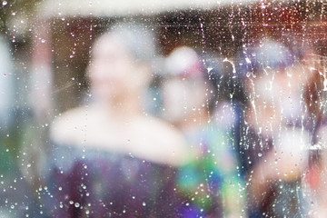 Water drops and steam behind glass, background blurred people playing water.
