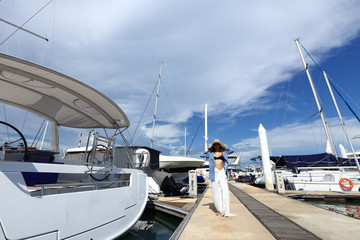 Fototapeta premium Mix Race Tanned skin Woman walk along Luxury Yachts in Marina Bay Club