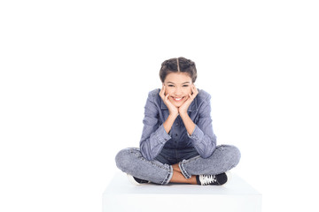 teenage student girl sitting on floor and looking at camera isolated on white