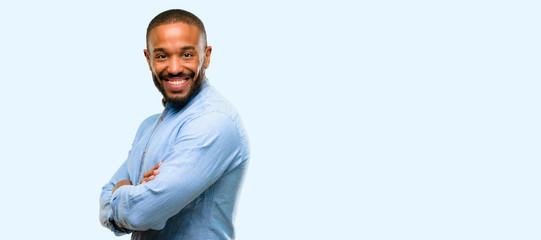 African american man with beard with crossed arms confident and happy with a big natural smile laughing isolated over blue background