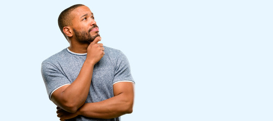 African american man with beard thinking and looking up expressing doubt and wonder isolated over...