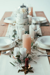 close up view of stylish table setting with candles, empty wineglasses and plates for rustic wedding