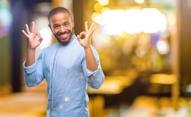 African american man with beard doing ok sign gesture with both hands expressing meditation and relaxation at night