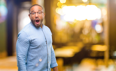 African american man with beard happy and surprised cheering expressing wow gesture at night