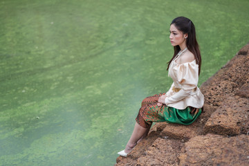 happy beautiful woman in Thai traditional dress near the pond