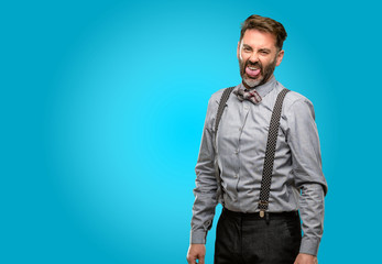 Fototapeta premium Middle age man, with beard and bow tie feeling disgusted with tongue out