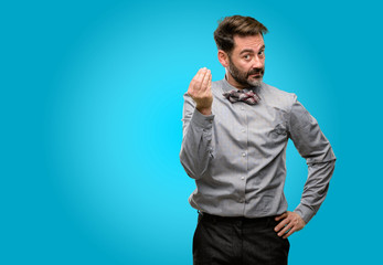 Middle age man, with beard and bow tie angry gesturing typical italian gesture with hand, looking...