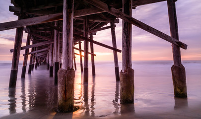 Fototapeta na wymiar a warm autumn sun sets over a california coast pier. Memories of summer and play